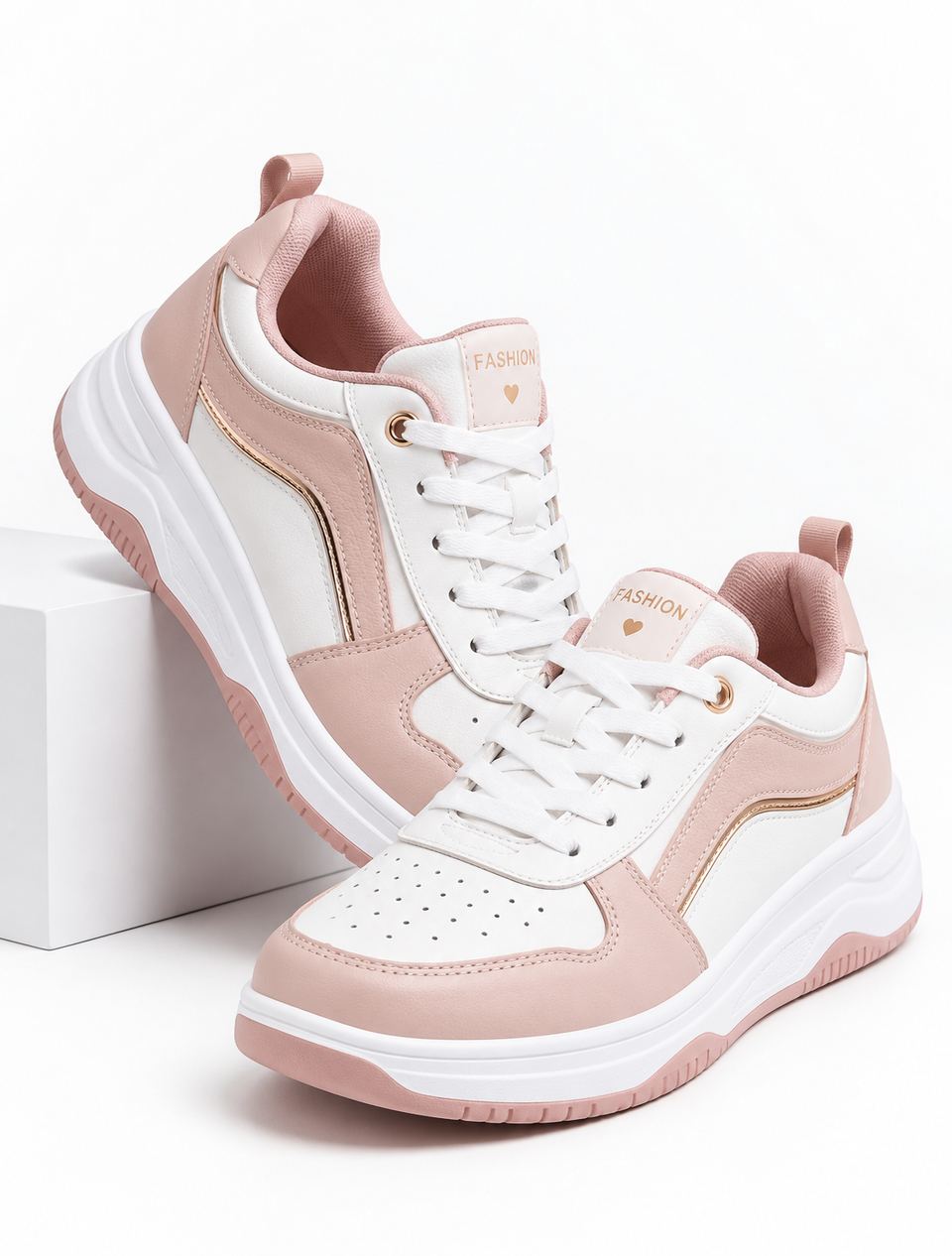 White and blush sneakers on a white studio block