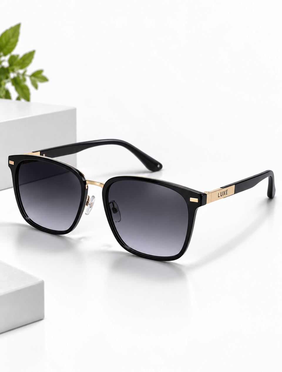 Black sunglasses with gold detailing on a white block